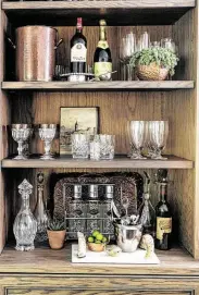 ??  ?? The breakfast room’s built-in bookshelve­s feature a charming bar that shows off some of Cynthia’s copper-pot collection.