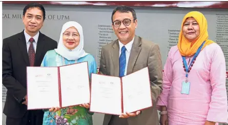  ??  ?? Prof Aini (second from left) and Dr Zabidi (second from right) exchange documents after the signing ceremony.