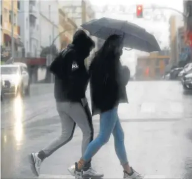  ?? ANDRÉS CARRASCO ?? Varias personas se resguardan de la lluvia bajo un paraguas.