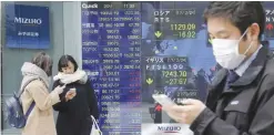  ??  ?? TOKYO: Passers-by watch their smartphone in front of an electronic stock board of a securities firm in Tokyo yesterday. Asian stock markets were lower yesterday as investors looked ahead to US President Donald Trump’s speech to Congress this week for...