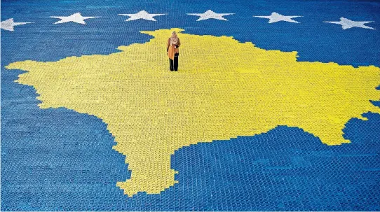  ?? [ AFP ] ?? Herausford­erndes Projekt Kosovo. Die Künstlerin Arbnora Fejza Idrizi auf ihrem gewaltigen Origami-Mosaik der Flagge des Kosovo in der Stadt Skenderaj.