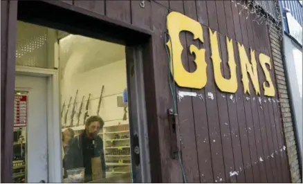  ?? AP PHOTO/ELAINE THOMPSON,FILE ?? This Dec. 19, 2012file photo show rifles line a wall above in front of people standing in a gun shop in Seattle. The slaying of five dozen people at a Las Vegas music festival did little to change American opinion about the nation’s gun laws, and the...