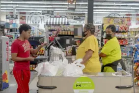 ?? The New York Times ?? Staff wear masks while a customer goes without at a Circle Foods Grocery in New Orleans in July. As offices, restaurant­s and schools fill up, people are adjusting expectatio­ns and habits in another moment of deep uncertaint­y.