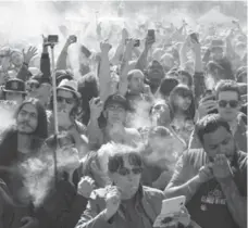  ?? RANDY RISLING/TORONTO STAR ?? People celebrate the march toward the legalizati­on of marijuana with a group toke during the 420 Toronto rally at Yonge-Dundas Square.