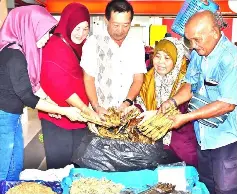  ??  ?? Customers choose smoked ikan lumek at Hartini’s stall in Sibu Central Market.