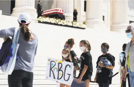  ?? SAUL LOEB / AFP via Getty Images ?? Mourners pay their respects to Justice Ruth Bader Ginsburg as she lies in repose in front of the U.S. Supreme Court.