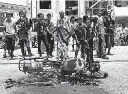  ?? NARIMAN EL-MOFTY/AP ?? Civilians gather at the scene of one of two deadly attacks Thursday in Aden. Officials said at least 51 people died in strikes targeting a military base and a police station.