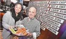  ?? Hearst Connecticu­t Media file photo ?? Fred Marcantoni­o, president and CEO of Sliders Grill & Bar, and Kristen Mikawa, the general manager at Sliders Middletown in the former Cypress Grill at 1265 South Main St., hold a plate of signature wings in the lounge in 2017.