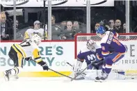  ??  ?? The Penguins’ Bryan Rust, left, scores the game winning goal in overtime against the Islanders.