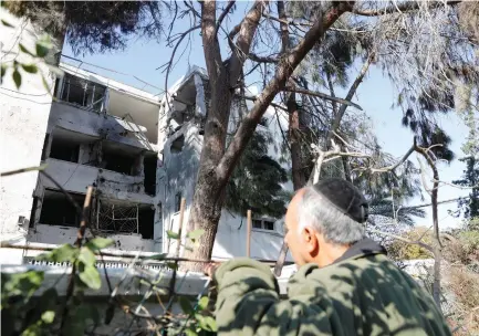  ?? (Ronen Zvulun/Reuters) ?? A MAN LOOKS towards an apartment building in Ashkelon damaged by a rocket fired from the Gaza Strip on Tuesday.