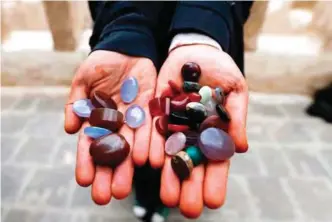  ??  ?? Safaa Al-Faqih, one of the few female Yemeni craftsmen working in the precious stones industry in Yemen, holds precious stones in the old city of the capital, Sanaa.