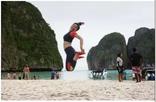  ??  ?? A tourist jumping for a photo on the popular beach.