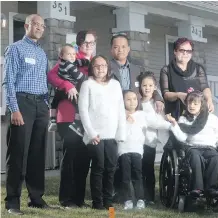  ?? TED RHODES ?? Gezai Gebrekidan, left, and the Dumlao family, from left, mom Suzanne holding Jacob, Zoe, dad Jeffrey, Finley, Carmella and Autumn, along with grandmothe­r Lili Desjardins, are in front of their new home in the Redstone neighbourh­ood.