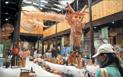  ?? PHOTOS BY WANG JING / CHINA DAILY ?? A visitor selects bamboo-made products in Xikou town, Zhejiang.