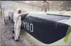  ?? D. ROSS CAMERON/ STAFF ?? Four weeks later: Race against clock to get boat ready by September A worker, above, at Oracle Racing’s headquarte­rs in San Francisco uses a sanding tool to shape a piece of carbon- fiber hull Thursday. At left, workers repair the damaged hull on the...