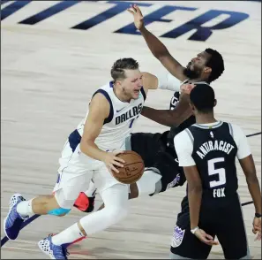  ?? PHOTOS BY STEPHEN M. DOWELL/ORLANDO SENTINEL/TNS ?? Above: The Mavericks' Luka Doncic (left) pushes through Sacramento Kings' Harrison Barnes (middle) and De’Aaron Fox (5) on Tuesday at Disney's ESPN Wide World of Sports in Orlando, Fla. Below: The Mavericks' Kristaps Porzingis (6) reaches to stop a drive by the Kings' De’Aaron Fox.