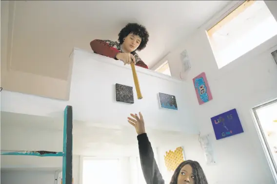  ?? Photos by Paul Kuroda / Special to The Chronicle ?? Stormy Adams, in the bedroom loft, hands a hammer to Mame Diarra Abdur-Rahman as they work on a tiny home in Berkeley, one of 25 planned units.