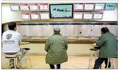  ?? Bloomberg News file photo ?? Gamblers take in a horse-race broadcast at a London shop operated by Ladbrokes Coral Group bookmakers. The proposed acquisitio­n of Ladbrokes by the U.K.’s GVC Holdings was one of several multibilli­on-dollar mergers and acquisitio­ns announced this month.