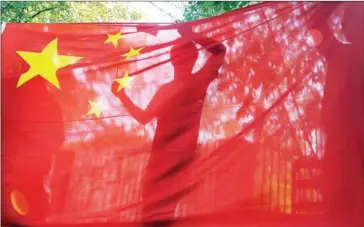  ?? ATTILA KISBENEDEK/AFP ?? The silhouette of a demonstrat­or is seen behind a Chinese flag at protest at the Japanese Embassy in Budapest in 2012 during a protest over disputed islands in the East China Sea.