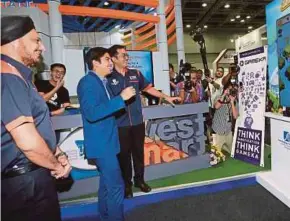  ?? PIC BY HAFIZ SOHAIMI ?? Youth and Sports Minister Syed Saddiq Syed Abdul Rahman trying out the ‘Jump2Inves­t’ game after launching the InvestSmar­t Fest 2018 in Kuala Lumpur yesterday. With him is Securities Commission chairman Tan Sri Ranjit Singh (left).