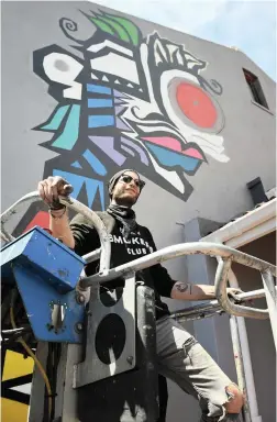  ??  ?? GETTING A LIFT: Internatio­nally acclaimed French artist Clement Mougel at work on a mural.