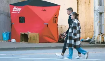  ?? TERRENCE ANTONIO JAMES/CHICAGO TRIBUNE ?? People pass by a tent at a homeless encampment on West Fulton Street near North Clinton Street in Chicago on Friday.