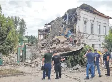  ?? ?? Efectivos de la Policía y residenes de Kharkov, norte de Ucrania, observan un edificio destruido por un misil ruso. (EFE).