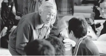  ?? FOTO: AP ?? >El emperador Akihito se arrodilla para hablar con una mujer durante visita a un campo de refugiados.