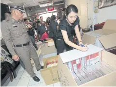  ??  ?? A police officer inspects food supplement­s seized during a warehouse raid in Bangkok’s Charan Sanitwong Soi 75.