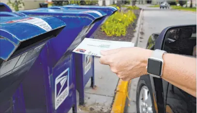  ?? The Associated Press file ?? A person drops an applicatio­n for a mail-in-ballot into a mailbox in Omaha, Neb., on Tuesday. White House chief of staff Mark Meadows rejected the legislatio­n the House passed late Saturday to provide $25 billion to the U.S. Postal Service.