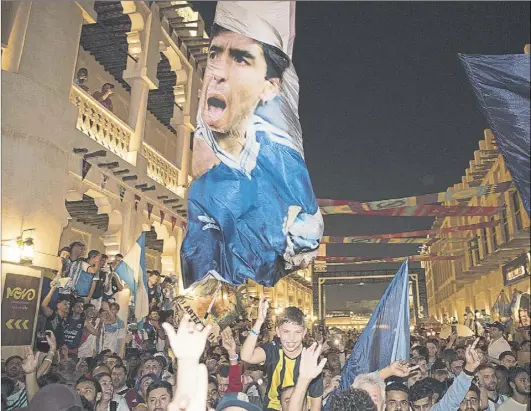  ?? Foto: j.j. sirvent ?? Reunión espontánea de aficionado­s argentinos ayer en el centro de Doha, portando una bandera descomunal con la imagen de Maradona
