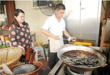  ??  ?? The couple getting the oil ready to start frying the gold cakes at Imbi Fried Gold Cake.