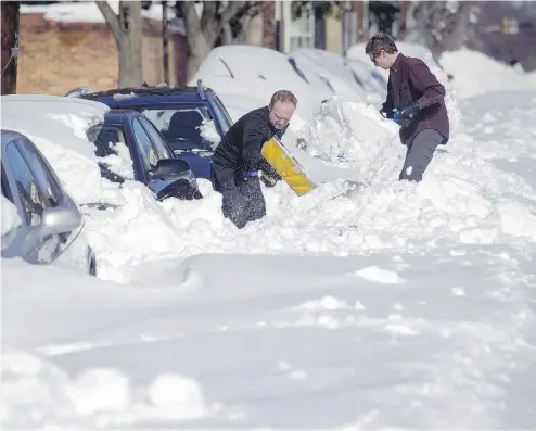  ?? CLIFF OWEN / THE ASSOCIATED PRESS ?? Two men work to shovel out their cars in Alexandria, Va., Sunday, after a mammoth blizzard with hurricane
force winds and record-setting snowfall brought much of the United States’ East Coast to an icy standstill.