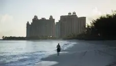  ?? Damon Winter, © The New York Times Co. ?? A man takes an early morning stroll on Paradise Beach on Paradise Island in the Bahamas in 2014. The Bahamas reopened this month to those who can present proof of a negative COVID-19 test taken within a week of arrival.