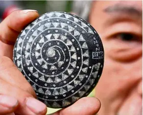  ?? - Photos: AFP ?? From Chinese characters to traditiona­l aboriginal totems, artist Wu rongbi has been selling intricatel­y painted pebbles on the streets in Taiwan for the last 40 years.