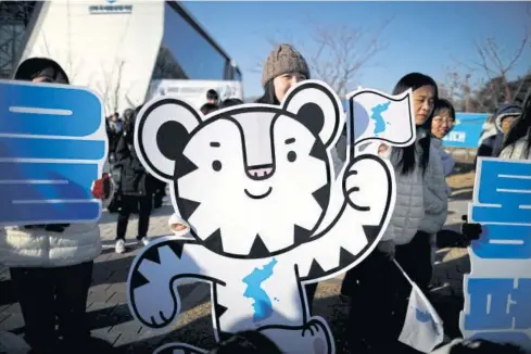  ??  ?? LEFT A fan carries a cutout of the Pyeongchan­g Olympics mascot Soohorang prior to a friendly match between the inter-Korean women’s ice hockey team and Sweden in Incheon last week.