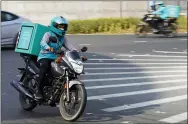  ?? JON GAMBRELL — THE ASSOCIATED PRESS ?? A delivery driver for the app Deliveroo speeds through a roundabout, in Dubai, United Arab Emirates, Thursday, Sept. 9, 2021. Advocates and workers say that casualties among food delivery riders are mounting in the city of Dubai, as the pandemic accelerate­s a boom in customer demand. The trend has transforme­d Dubai’s streets and drawn thousands of desperate riders, predominan­tly Pakistanis, into the high-risk, lightly regulated and sometimes-fatal work.