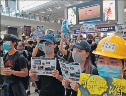  ?? / T. SIU (REUTERS) ?? Un grupo de manifestan­tes, ayer en el aeropuerto de Hong Kong. Llevan un ojo tapado en señal de protesta después de que una joven haya perdido la visión de un ojo por una carga policial el domingo.