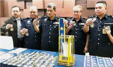  ??  ?? Major haul: Comm Asri (centre) and his team showing the medals and other items that were seized during the ceremony in Alor Setar.