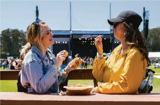  ?? Grace Li / The Chronicle 2019 ?? Above: Festivalgo­ers eat a sushirrito and tater tots at Outside Lands in 2019. This year, the festival is hosting 94 restaurant­s, including 18 new additions. Right: The chicken sandwich from Fowl + Fare.