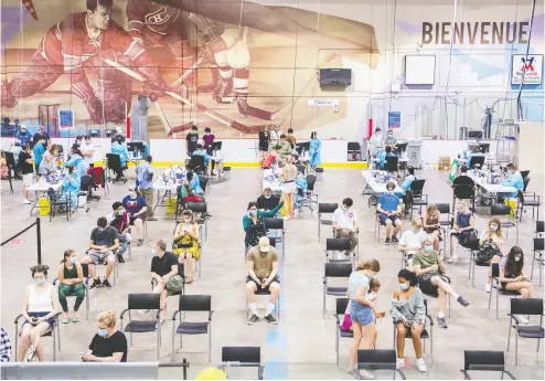  ?? GRAHAM HUGHES / THE CANADIAN PRESS FILES ?? People wait their turns last Saturday at the Bill Durnan Arena COVID-19 vaccinatio­n site in Montreal.