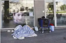  ?? — AP ?? MILNA: A homeless sleeps under blankets in front of the entrance of a bank, in Milan yesterday.