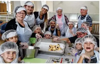  ??  ?? Résidents, bénévoles et enfants du centre de loisirs présentent les poires au chocolat confection­nées avec Lino Gonçalves.