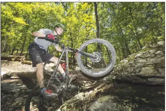  ?? NWA Democrat-Gazette/BEN GOFF @NWABENGOFF ?? Graham Hassion, a trailbuild­er with Rogue Trails, takes an optional technical line on the Karst Loop June 8 during the grand opening of the Monument Trails at Hobbs State Park.