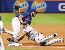  ?? THJE ASSOCIATED PRESS ?? The New York Mets’ Amed Rosario, top, looks for the call after beating the tag by Atlanta Braves third baseman Johan Camargo for a triple Tuesday in New York.