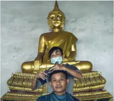  ?? AFP ?? A man gets a free haircut at a Buddhist temple near the Grand Palace, where thousands of people have been gathering to pay their respects to the late Thai King Bhumibol Adulyadej, in Bangkok on Saturday. —