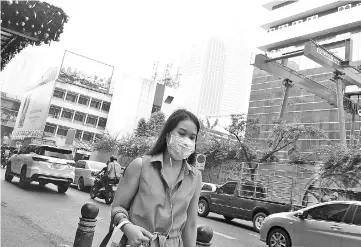  ??  ?? A woman wears a face mask on the way to work while smog blankets Bangkok. — AFP photo