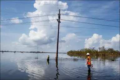  ?? CHRIS GRANGER — THE TIMES-PICAYUNE — THE NEW ORLEANS ADVOCATE VIA AP ?? Utility crews stand in water as they work on repairing power lines along Highway 23in Plaquemine­s Parish, La., over a week after Hurricane Ida on Sept. 7.