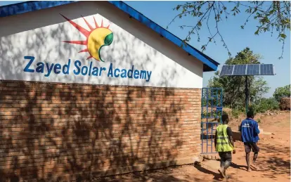  ??  ?? Clockwise from above, the Zayed Solar Academy in Malawi; students of the women-only course at the academy practise the skills they have learned; solar-powered equipment a barber uses to run his hair-cutting and phonecharg­ing business; children read by...