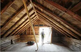  ?? PHOTOS BY BOB ANDRES / BANDRES@AJC.COM ?? Trevor Beemon, executive director of the Root House, checks out the view from the attic in the pioneer cabin. The second floor of the cabin will be used by Cobb Landmarks for an exhibit on slavery, which is an “important part of the story that we need to tell at this house,” Beemon said.